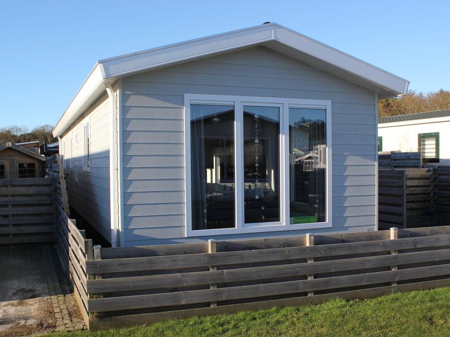 Chalet Bregkoog 232 in De Koog, Texel, met houten omheining en grote ramen, ideaal vakantiehuis op de Waddeneilanden.