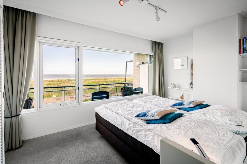 Schlafzimmer mit Meerblick in Appartement Juliana 160 Zeezicht, De Koog, Texel. Wachen Sie mit einem atemberaubenden Blick ueber die Duenen auf.