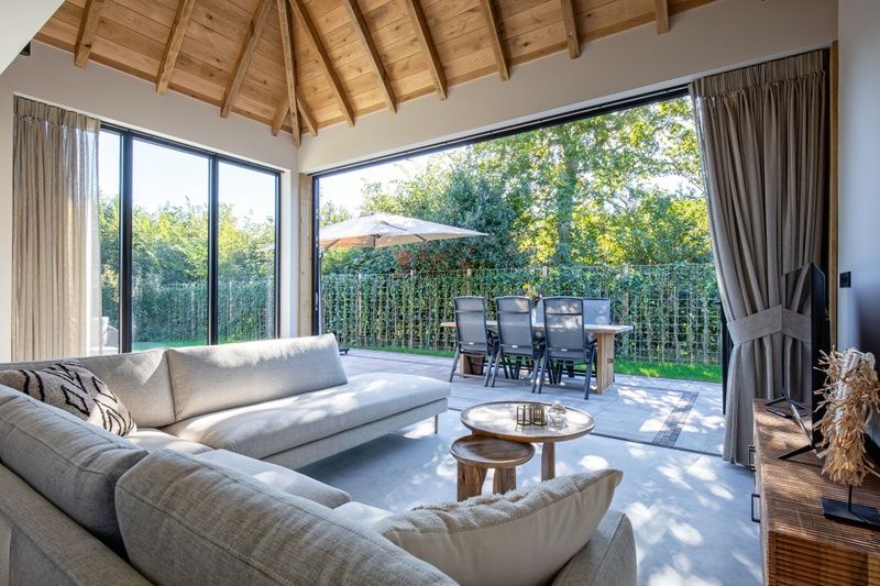 Ruime woonkamer met openslaande deuren naar tuin van Villa Flo in De Koog, Texel.