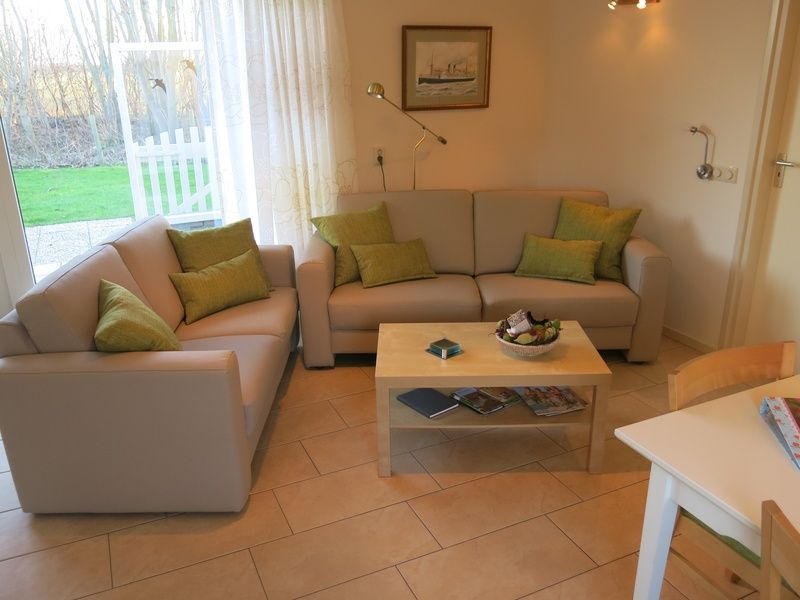 Gezellige woonkamer van Bungalow 't Luwe Land 49 in De Koog Texel, met comfortabele banken en uitzicht op de natuur van de Waddeneilanden.