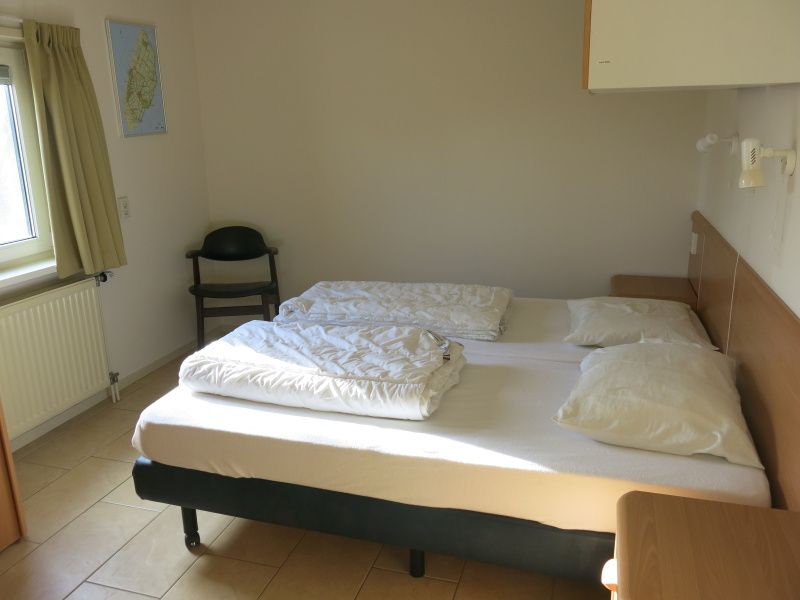 Lichte tweede slaapkamer in Bungalow 't Luwe Land 49 De Koog Texel, voorzien van comfortabele bedden voor een rustgevend verblijf op de Waddeneilanden.