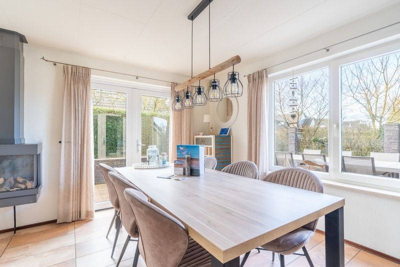 Eetkamer met uitzicht op de tuin in Vakantiehuis Kamperfoelie 81, De Koog, Texel, perfect voor gezellige maaltijden.