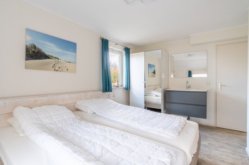 Lichte slaapkamer in Vakantiehuis Kamperfoelie 81, De Koog, Texel, met comfortabele bedden en uitzicht op de tuin.