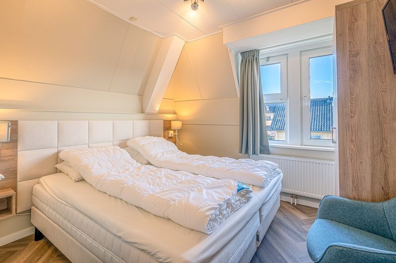 Gezellige slaapkamer in Appartement Zeedistel 22, De Koog, Texel, met comfortabele bedden en veel natuurlijk licht.