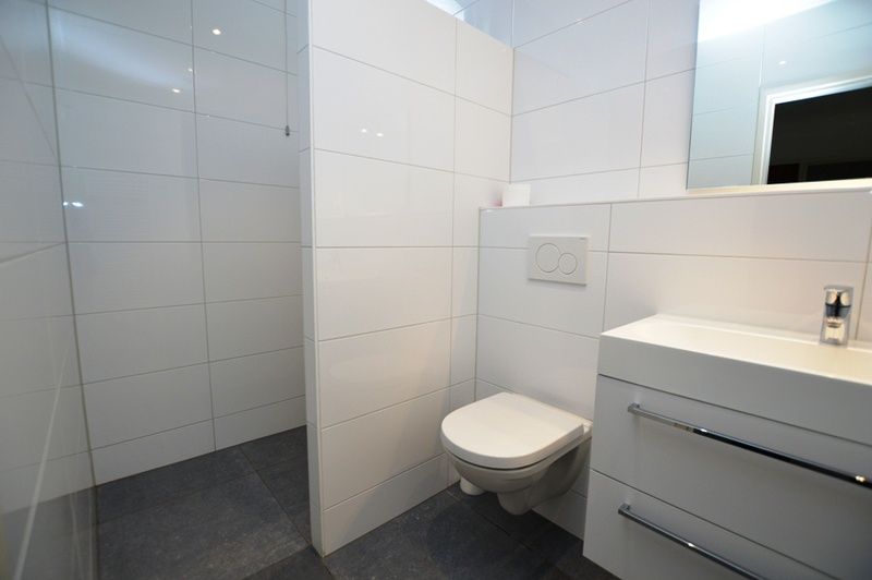 Modernes Badezimmer im Ferienhaus Epelaan 31, De Koog, Texel, mit glatten weissen Fliesen und Toilette.