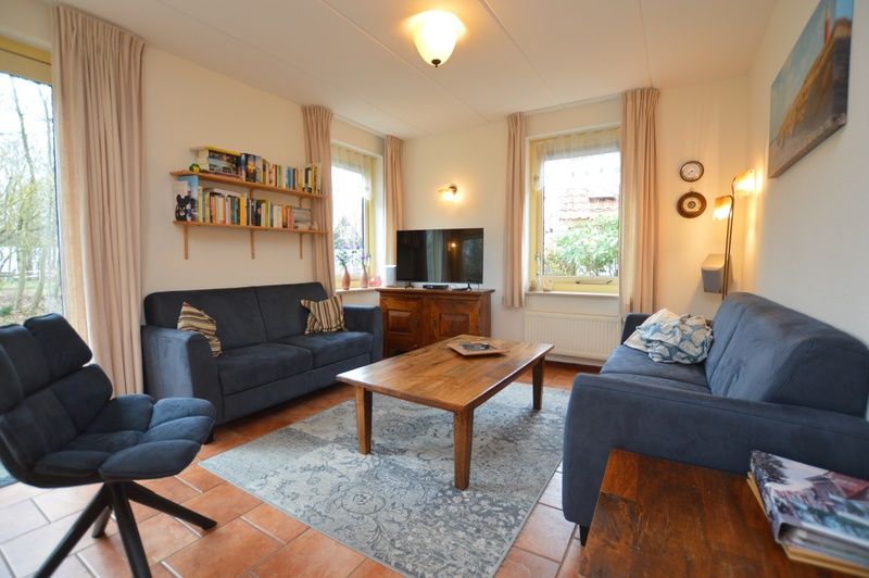 Ruime zithoek in Vakantiehuis 7K, De Koog, Texel met boekenplank en uitzicht op de tuin.