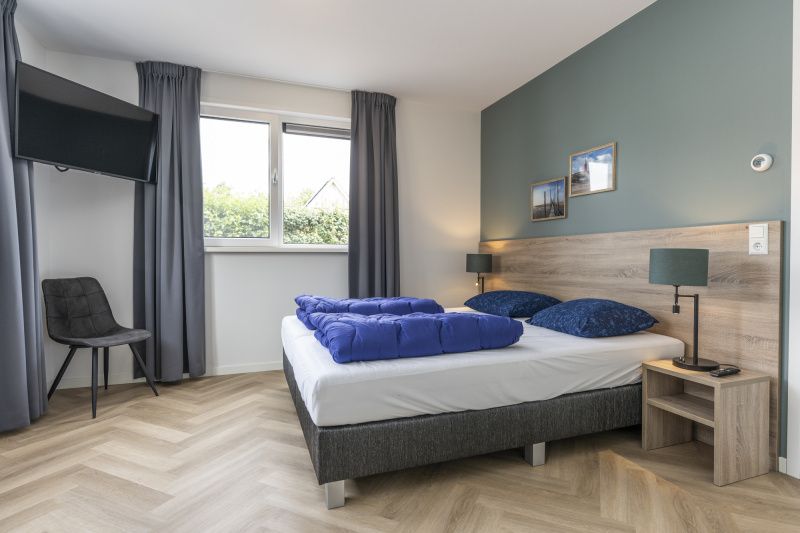 Cozy bedroom in Villa 39 De Koog Texel with large window and double bed.