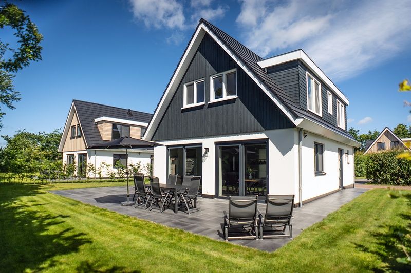 Back side of Villa 39 vacation home De Koog Texel with garden and deck chairs.