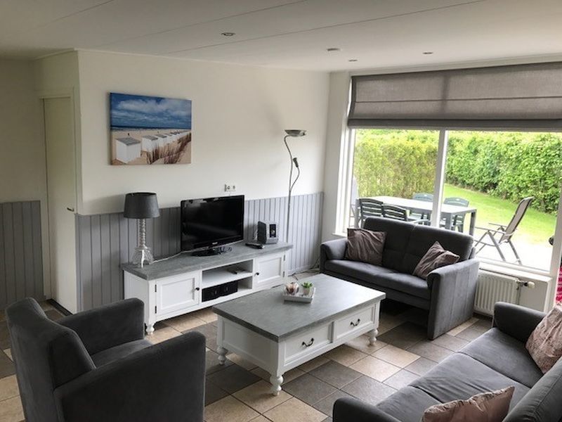 Ruime zithoek in Bungalow 25, De Koog Texel, met uitzicht op de tuin van de Waddeneilanden.