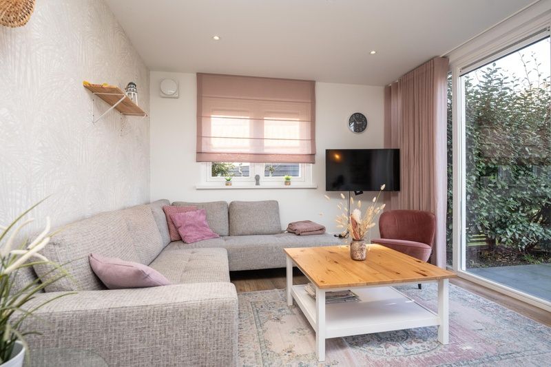 Gezellige woonkamer van vakantiehuis Mienterbos - Heideglop in De Koog, Texel, met comfortabele zithoek en groot raam met uitzicht op de tuin.