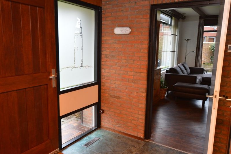 Ingang van Orchismient 28 in De Koog Texel met bakstenen muren en glazen deur.