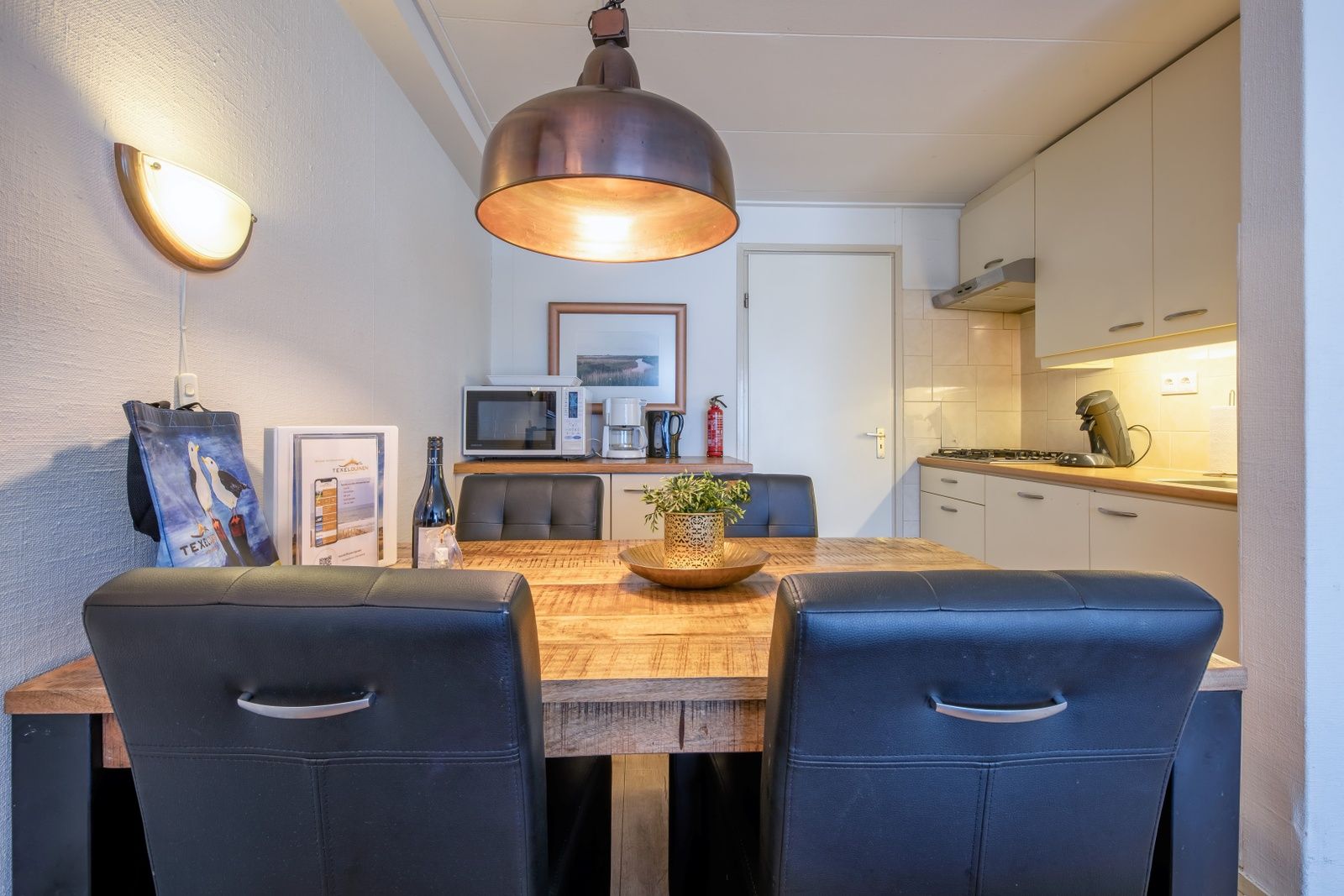 Eetgedeelte in Appartementen Anna - de Zeehond, De Koog, Texel met houten tafel en moderne keukenapparatuur.