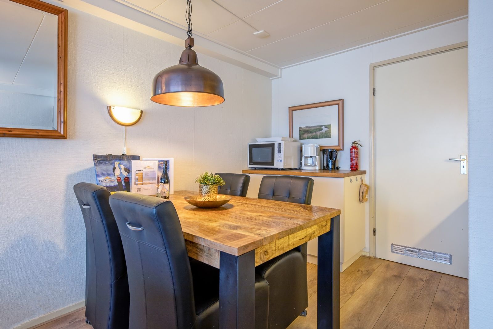 Gezellige eethoek in Appartementen Anna - de Zeehond, De Koog, Texel met stijlvolle lampen en houten interieur.