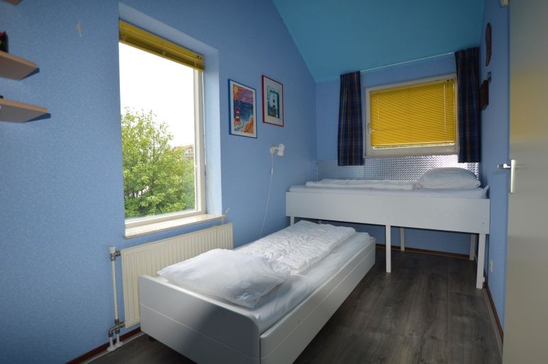 Ruime zolderkamer in Vakantiehuis Stappeland 111, De Koog, Texel met comfortabel tweepersoonsbed en sfeervolle verlichting.