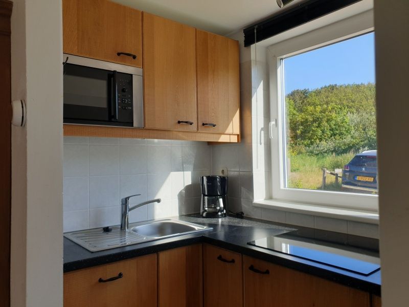 Moderne Kueche von De Duinpan - Duinhuisje Texel in De Koog, Texel, mit Blick auf die gruene Umgebung.