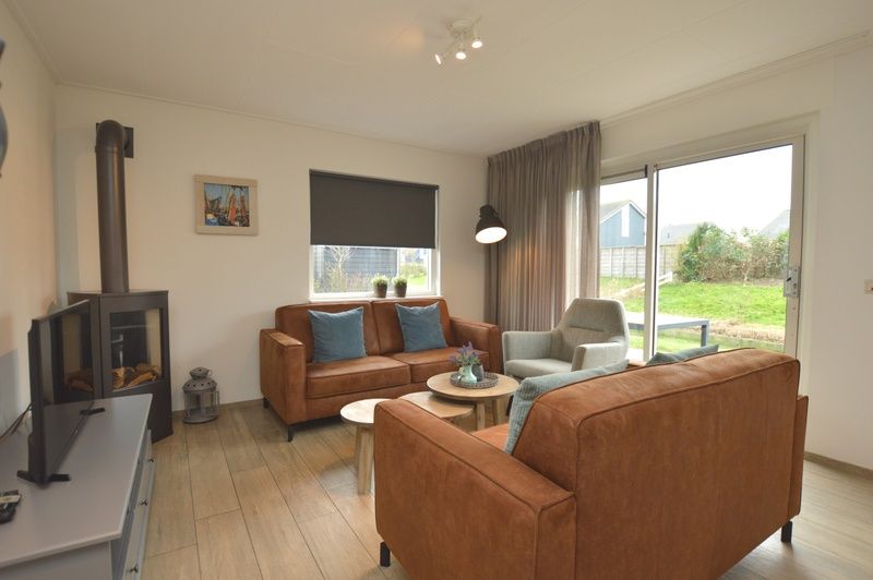 Gemuetliches Wohnzimmer des Ferienhauses Stappeland 215 in De Koog, Texel, mit bequemer Sitzecke und Gartenblick.
