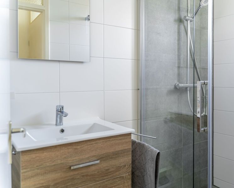 Moderne badkamer in vakantiehuis De Anemoon, De Koog, Texel. Stijlvolle douche en wastafel met houten afwerking.