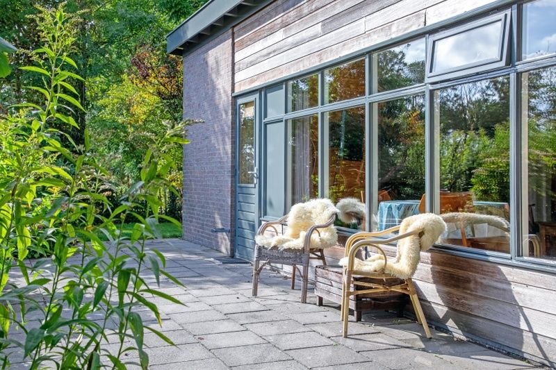 Zonnig terras bij De Zonneweelde vakantiehuis in De Koog, Texel, omringd door natuur.