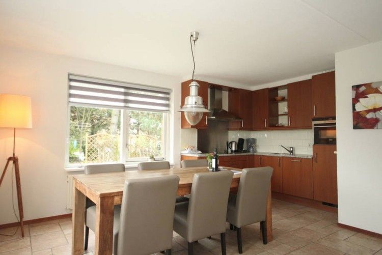 Gezellige eetkamer in 6 Persoons luxe villa met sauna in De Koog, Texel, met houten tafel en keuken.