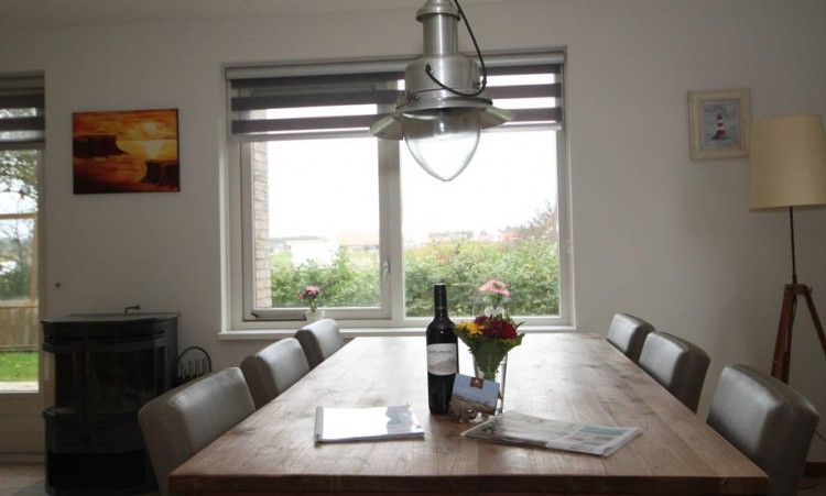 Eettafel met wijn en bloemen in 6 Persoons luxe villa met sauna in De Koog, Texel, met tuinzicht.