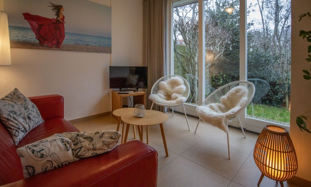 Knusse zithoek in vakantiehuis Zusje van 17, De Koog, Texel met comfortabele stoelen en tuinzicht.