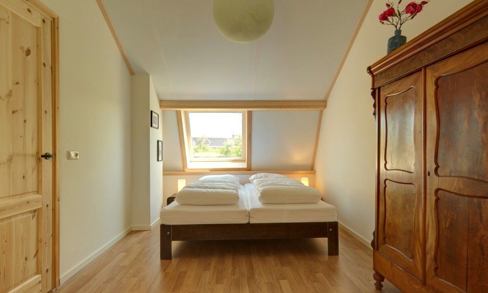 Lichte slaapkamer in vakantiehuis Zusje van 17, De Koog, Texel met houten vloer en groot raam.