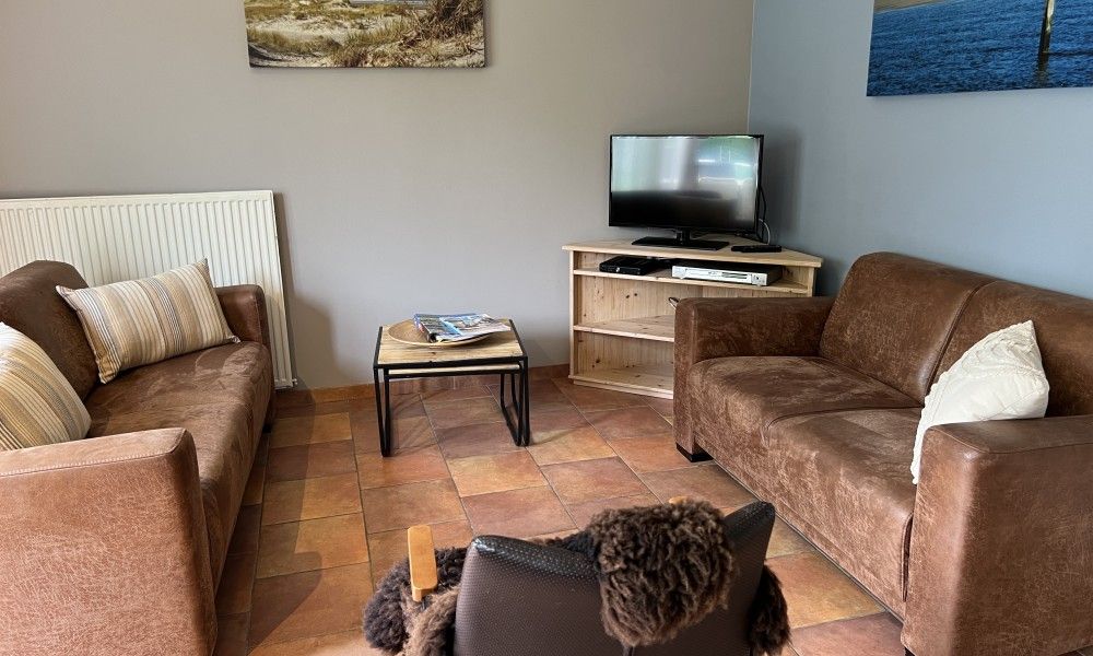 Gezellige woonkamer in Koetshuis vakantiehuis, De Koog Texel, met comfortabele zithoek en rustieke inrichting op de Waddeneilanden.
