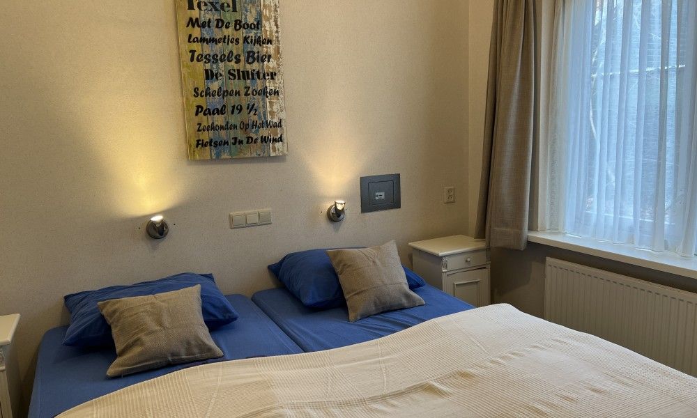 Gezellige slaapkamer in Koetshuis vakantiehuis, De Koog, Texel. Comfortabele bedden en warme verlichting voor een ontspannen verblijf op de Waddeneilanden.