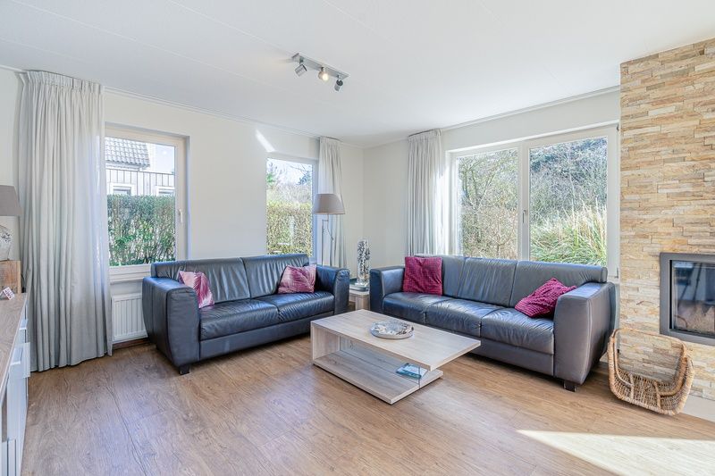 Cozy living room of Holiday home Honeysuckle 95 in De Koog, Texel with comfortable sofas and fireplace.
