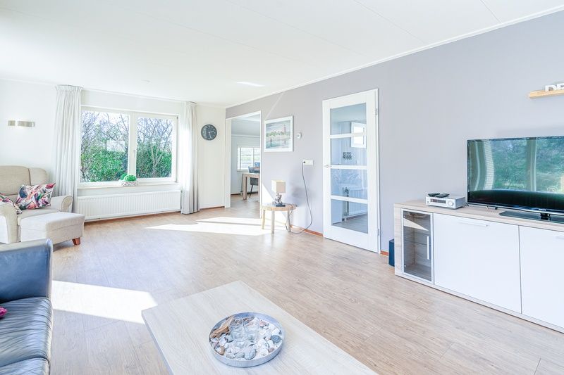 Spacious living room in Holiday Home Honeysuckle 95, De Koog, Texel with lots of natural light and views of the garden.