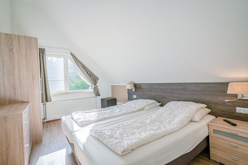 Cozy bedroom in Holiday home Honeysuckle 95, De Koog, Texel overlooking the green surroundings.