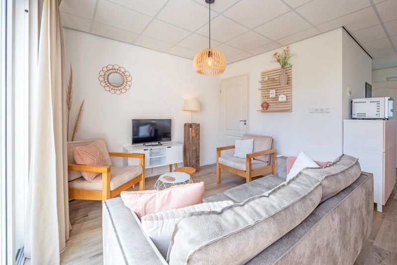 Stijlvolle zithoek in De Duinroos, Texel, met moderne inrichting en natuurlijke lichtinval.