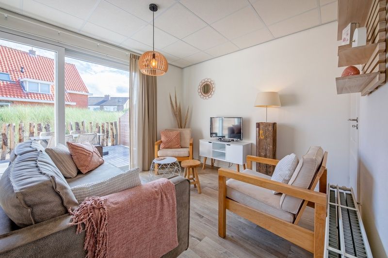 Lichte woonkamer van De Duinroos vakantiehuis in De Koog, Texel met toegang tot terras.