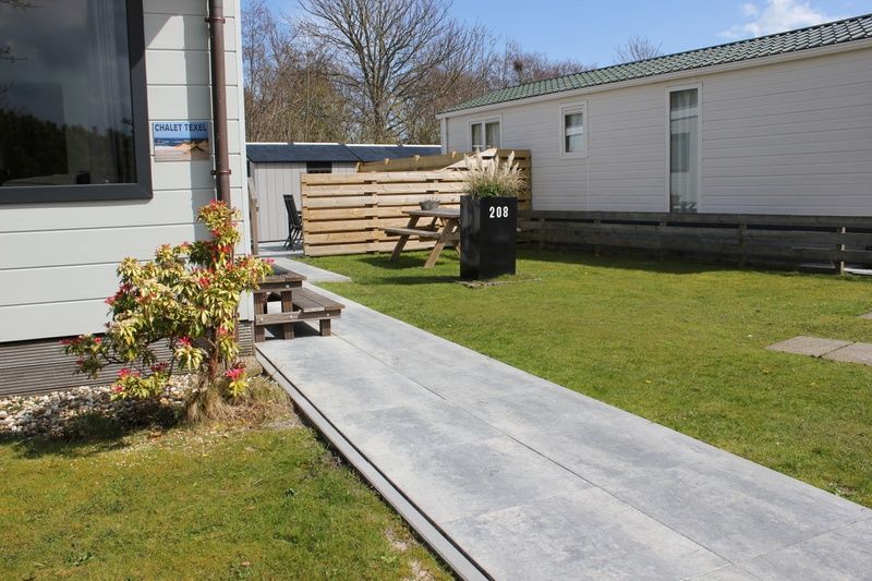 Chalet Bregkoog 208 in De Koog, Texel, met een ruim terras en een groene omgeving voor een ontspannen vakantie.