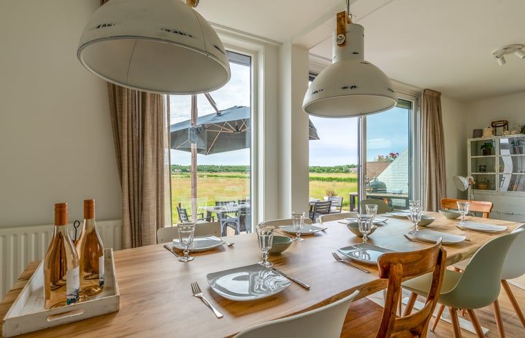 Eetkamer in Huisje in De Koog, Texel, met grote tafel en uitzicht op de natuur van de Waddeneilanden.