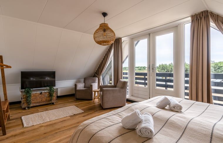 Luxe slaapkamer in Huisje in De Koog, Texel, met balkon en uitzicht op de Waddeneilanden.