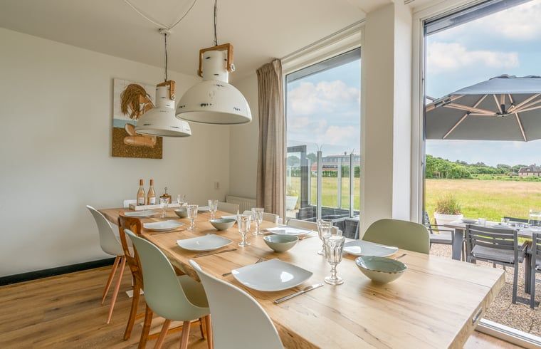 Eetkamer met uitzicht op de natuur in Huisje in De Koog, Texel, ideaal voor gezellige diners.