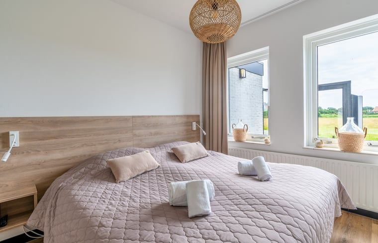 Slaapkamer in Huisje in De Koog, Texel, met uitzicht op de tuin en comfortabele bedden.