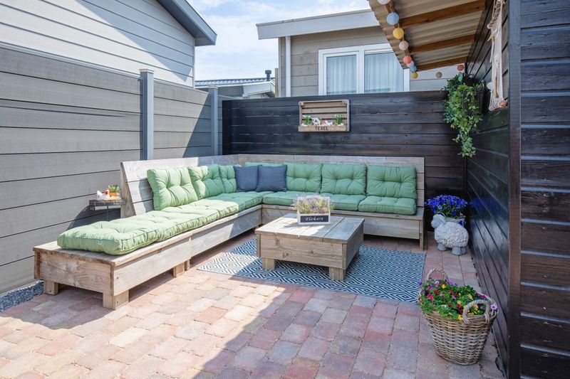 Stijlvolle loungehoek met groene kussens bij Chalet Bregkoog 88 in De Koog, Texel, op Chaletpark Bregkoog.