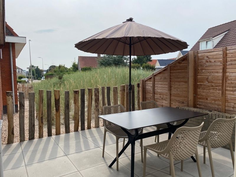 Sonnenterrasse mit Sonnenschirm und Sitzgelegenheiten in De Boomleeuwerik, Ferienhaus in De Koog.