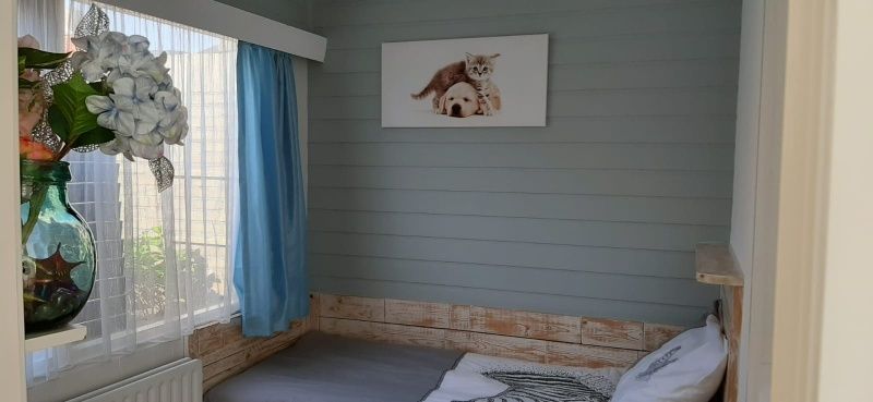 Knusse slaapruimte in Appartement Duinzee Texel, De Koog, met grote ramen voor natuurlijk licht.