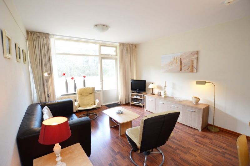 Gezellige zithoek in Appartement Kerckeland 24, De Koog, Texel met uitzicht op de tuin en veel natuurlijk licht.