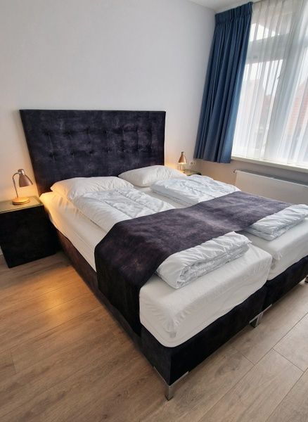 Stijlvolle slaapkamer in Vakantiehuis Duinzee Texel, De Koog, met groot raam en natuurlijke lichtinval.