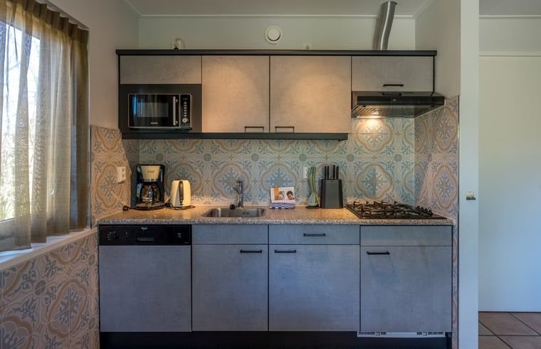 Moderne keuken met tegelwand in vakantiehuisje in De Koog, Texel.