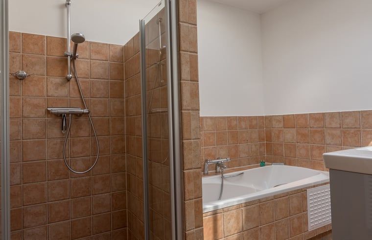 Badkamer met douche en bad in vakantiehuisje in De Koog, Texel.