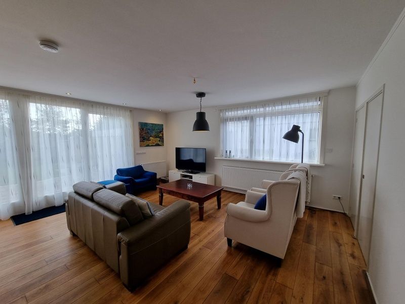 Helles und geraeumiges Wohnzimmer im Bungalow Epelaan 13, De Koog, Texel. Ferienhaus mit stilvoller Einrichtung und grossen Fenstern.