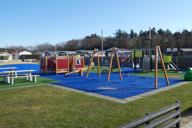 Uitgebreide speeltuin bij Chalet Bregkoog 27, De Koog Texel, met schommels en klimrekken voor kinderen.