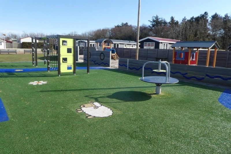 Kindvriendelijke speelruimte bij Chalet Bregkoog 27, De Koog, met diverse speeltoestellen en grasvelden.