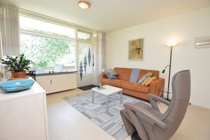 Lichte woonruimte in Appartement Kerckeland 64, De Koog, Texel met grote ramen en uitzicht op groen.