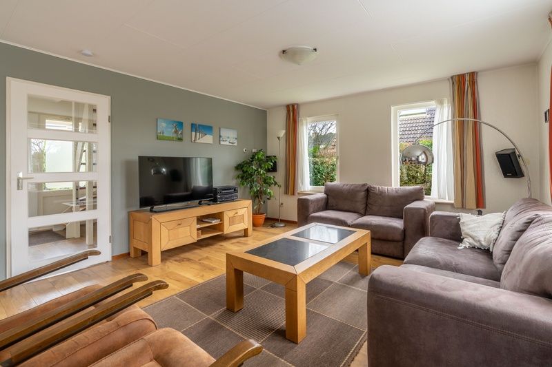 Moderne woonkamer van Vakantiehuis Kamperfoelie 43 met sauna in De Koog, Texel, met flatscreen-tv en houten meubels.